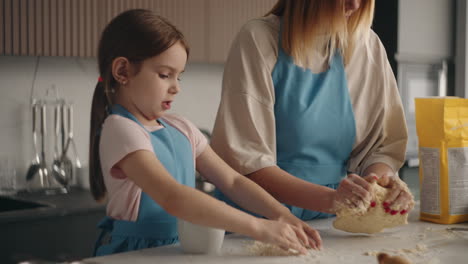 Das-Süße-Kleine-Mädchen-Lernt,-Teig-Am-Tisch-Der-Heimischen-Küche-Zu-Kochen-Und-Hilft-Ihrer-Mutter